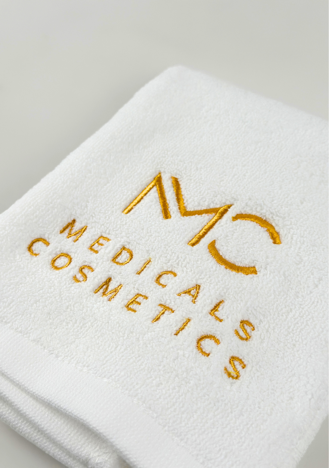 TOWEL MEDICALS COSMETICS SMALL WHITE, GOLDEN LOGO 
Malý bavlnený uterák Medicals Cosmetics biely so zlatou výšivkou